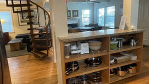 Una cocina con estantes de madera, una estufa empotrada y un comedor con mesa y sillas.