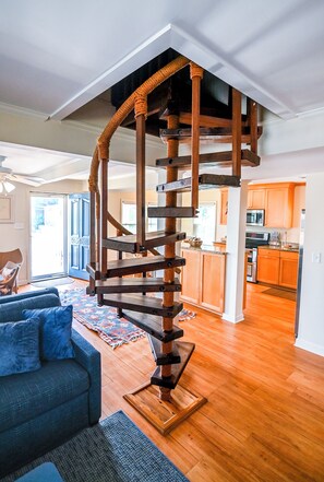 Eine Wendeltreppe mit Holzvertäfelung und Seilgeländern, die zu einer oberen Etage führt.