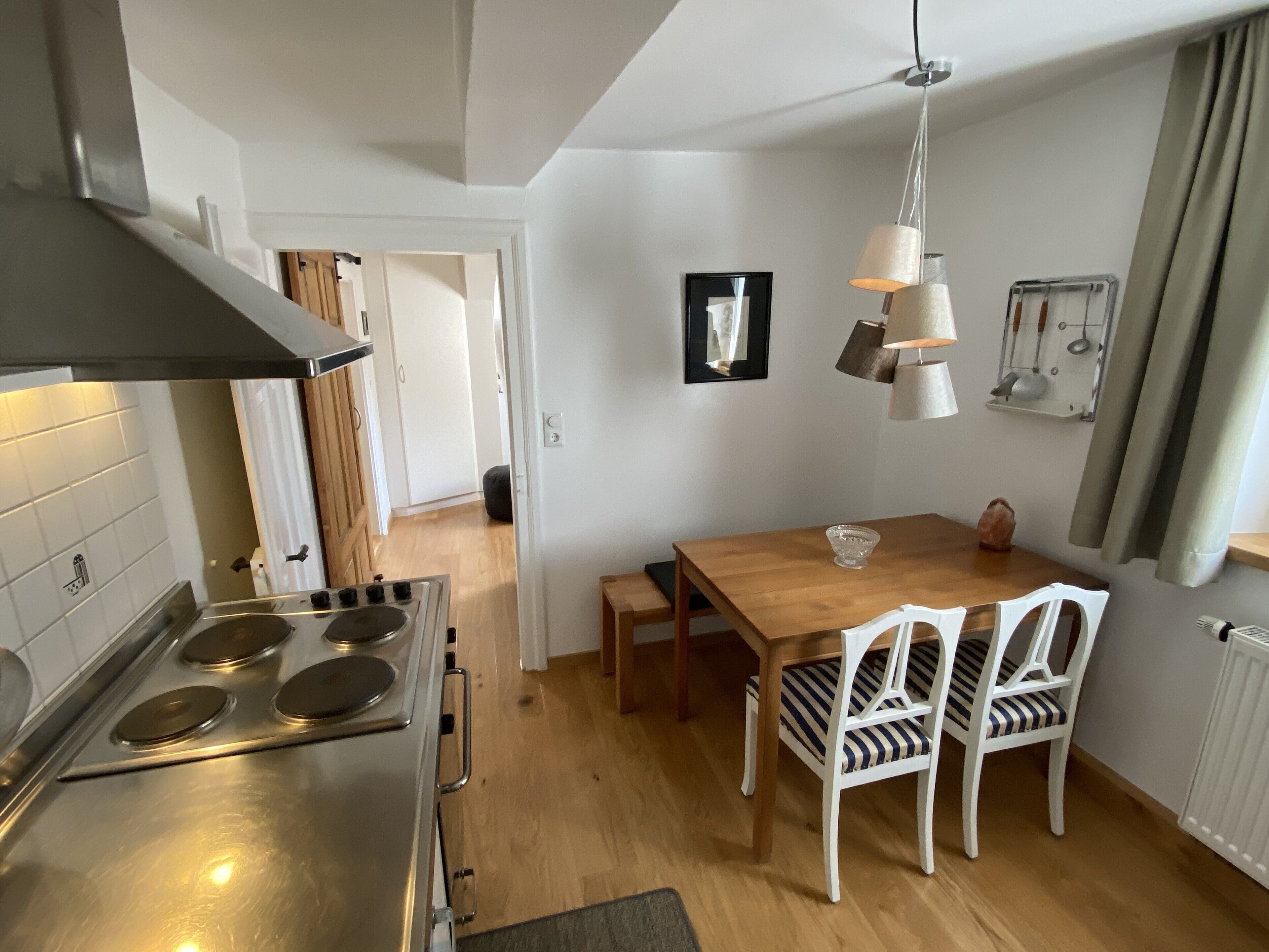 Una cucina moderna con piano cottura in acciaio inossidabile, tavolo da pranzo in legno e sedie bianche.