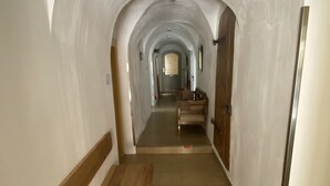En gang med hvælvet loft, træbænke og flisegulv.