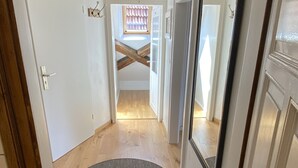 Un pasillo con suelo de madera, un tapete redondo y un espejo grande a la derecha.