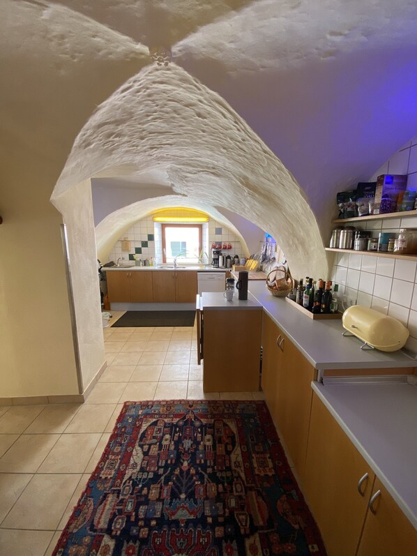 Eine Küche mit gewölbter Decke, einer zentralen Kochinsel und einem gemusterten Teppich.