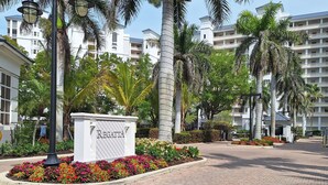 A hotel entrance with a sign reading "Regatta," surrounded by palm trees and flower beds. - Regatta Resort, Vanderbilt Beach, Naples, 6 minute walk to beach (Naples)