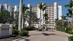 A gated entrance with a sign reading "Regatta" surrounded by palm trees and a multi-story building with balconies. - Regatta Resort, Vanderbilt Beach, Naples, 6 minute walk to beach (Naples)