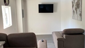 A living room with two brown sofas, a flat-screen TV mounted on the wall, and a world map artwork. - Hidden WineCountry Gem 1 Downstairs Unit (Santa Rosa)