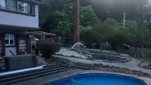 A swimming pool with a wooden deck, surrounded by a landscaped garden with trees and a palm tree. - Hidden WineCountry Gem 1 Downstairs Unit (Santa Rosa)