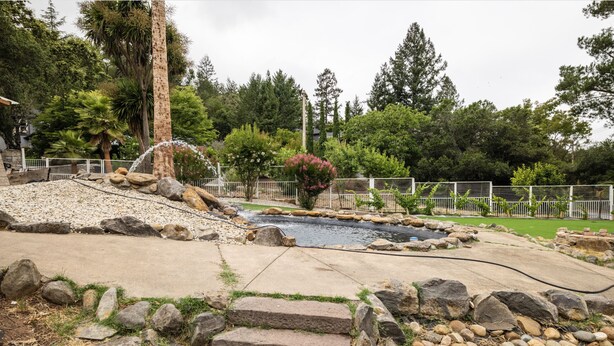 A landscaped garden with a water feature, stone steps, and a fenced area. - Hidden WineCountry Gem 1 Downstairs Unit (Santa Rosa)