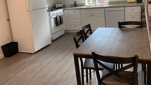 A modern kitchen with white cabinets, a refrigerator, stove, and a dining table with chairs. - Hidden WineCountry Gem 1 Downstairs Unit (Santa Rosa)