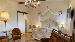 Una camera da letto con un letto grande, due poltrone, un tavolino e un lampadario.