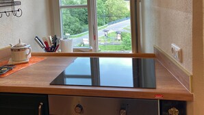 Una cucina con un'ampia finestra, un fornello e un piano di lavoro con utensili da cucina.