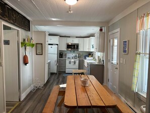 A compact kitchen with white cabinets, a wooden table, and a microwave.