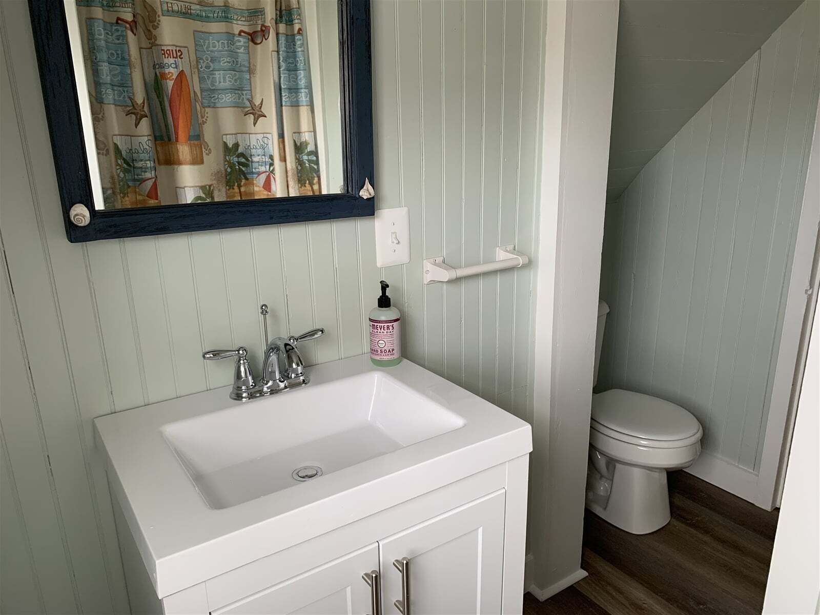 A bathroom with a white sink, a mirror, and a toilet.