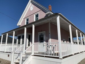 A pink house with a porch and white railings.
