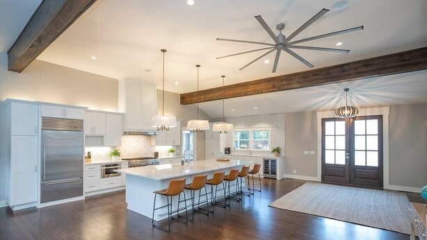 A spacious kitchen with a large island, bar stools, and a ceiling fan. - Lakefront Home! Game Tables and Boat Dock (Hendersonville)