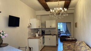 A compact living space with a kitchen, dining area, and a sofa. - Kristallzimmer - Urlaub auf dem Historischen Weingut (Maring-Noviand)