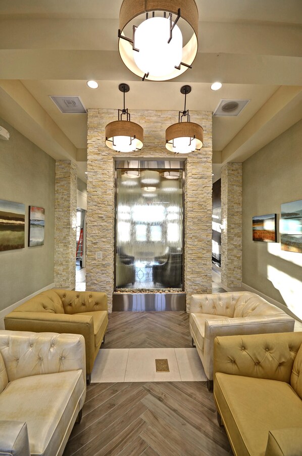 A lobby with a stone wall, two chandeliers, and a reception desk.