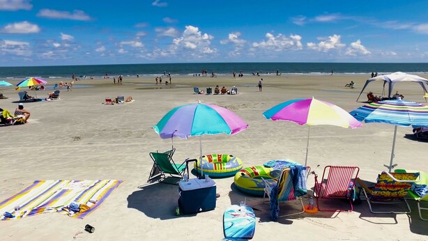 A beach with colorful umbrellas, beach chairs, and inflatable toys.