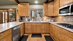 Una cocina con armarios de madera, lavavajillas de acero inoxidable, microondas y estufa a gas.