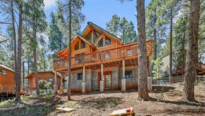 A two-story log cabin with a balcony, surrounded by tall pine trees. - Kachina Tree House | 3BR | | Spend Spring in Flagstaff! (Flagstaff)