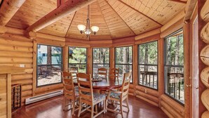 A log cabin with a wooden dining table and chairs, large windows, and a wooden ceiling. - Kachina Tree House | 3BR | | Spend Spring in Flagstaff! (Flagstaff)