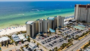 Ein Strandhotel mit mehreren Hochhäusern, einem Parkplatz und einem Strand mit Sonnenschirmen.