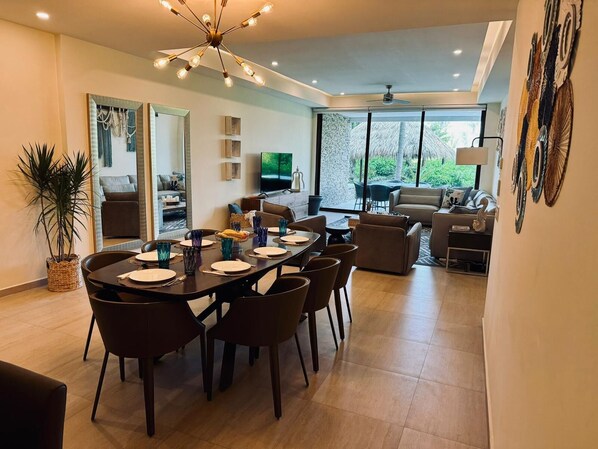 A modern living room with a dining area, large windows, and a view of the outdoors.