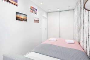 Ein modernes Schlafzimmer mit einem Bett, einem Kleiderschrank und drei gerahmten Bildern an der Wand.