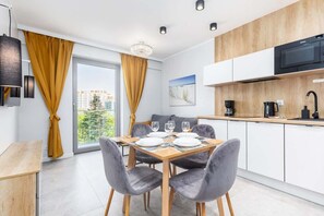 Eine moderne Küche mit weißen Schränken, einer Mikrowelle und einem Essbereich mit Tisch für vier Personen.