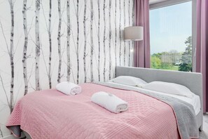 A bedroom with a bed, a window, and a wall with a tree pattern.