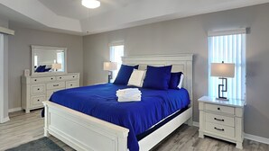 Een slaapkamer met een groot bed, twee nachtkastjes, een kaptafel en een spiegel.