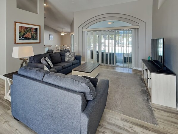 Una sala de estar moderna con un sofá gris, una mesa de centro y un televisor sobre un mueble.