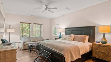 A bedroom with a bed, a desk, a chair, a sofa, a lamp, and a ceiling fan.