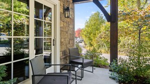 A covered patio area with stone walls, large windows, and outdoor furniture.