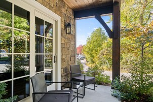 Un patio cubierto con paredes de piedra, ventanas amplias y mobiliario exterior.
