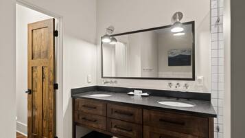 A bathroom with two sinks, a large mirror, and wooden cabinetry.