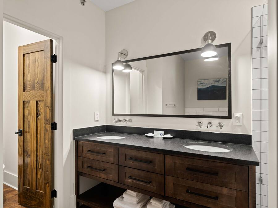 A bathroom with two sinks, a large mirror, and wooden cabinetry.