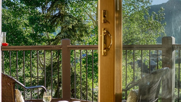 A wooden-framed glass door leading to an outdoor deck with a table, chairs, and a book.
