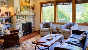 A cozy living room with a stone fireplace, leather sofas, a coffee table, and a bookshelf.