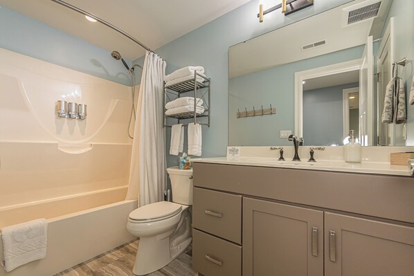 A bathroom with a bathtub, toilet, and vanity with a mirror.