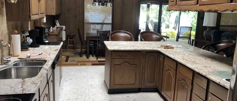 Une cuisine dotée de meubles en bois, de plans de travail en granit et d’un coin repas avec des chaises et une table.