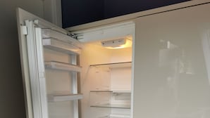 Un réfrigérateur ouvert, doté de plusieurs étagères et d’un compartiment congélateur.