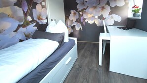 Une chambre à coucher avec un lit, un bureau et une fresque florale sur un mur.