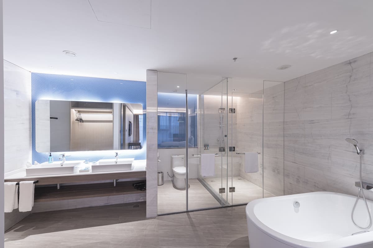 Un baño moderno con una bañera grande, una ducha con mampara de vidrio y un lavamanos con espejo.