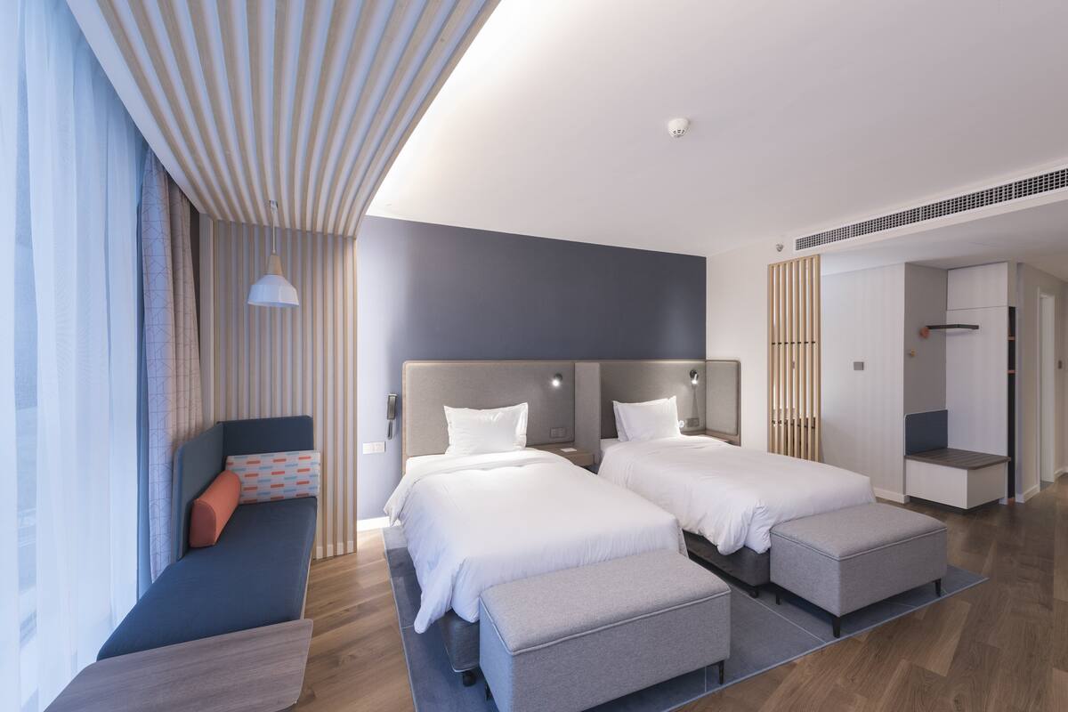 Una habitación de hotel moderna con dos camas, zona de estar y kitchenette.