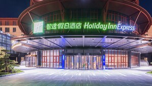 Fachada moderna de un hotel Holiday Inn Express, con diseño curvo y puertas de vidrio.