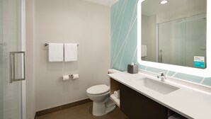 A modern bathroom with a glass shower enclosure, a white toilet, a sink with a mirror, and a towel rack. - avid hotel Ft Lauderdale Airport – Cruise by IHG (Fort Lauderdale)