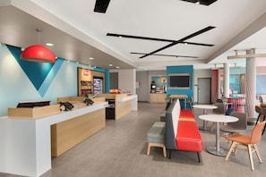A modern interior with a reception desk, seating area, and a kitchenette. - avid hotel Ft Lauderdale Airport – Cruise by IHG (Fort Lauderdale)