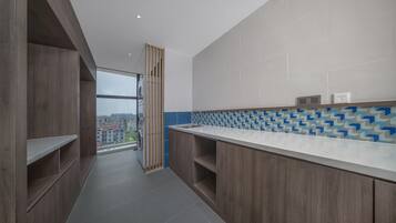 Una cocina moderna con lavadora integrada, armarios de madera y vistas a la ciudad a través de un amplio ventanal.