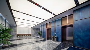 A modern elevator area with marble flooring and blue paneling.