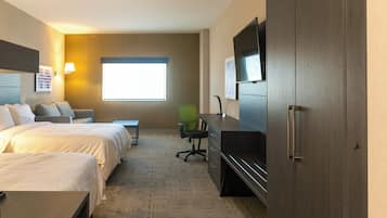 A hotel room with two beds, a desk, a chair, a television, and a window.